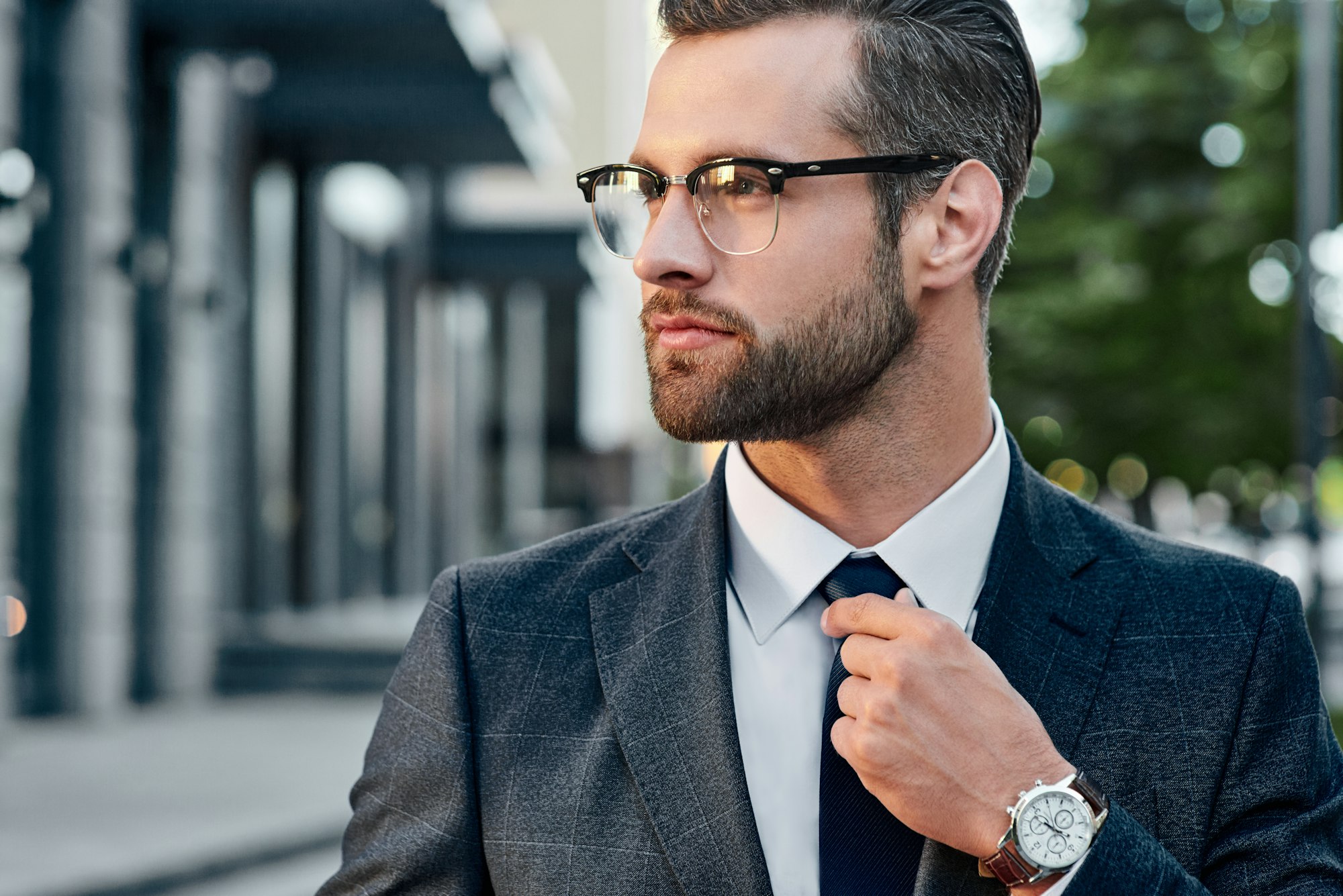 The young in spectacles men straightens his tie, his face unshaven